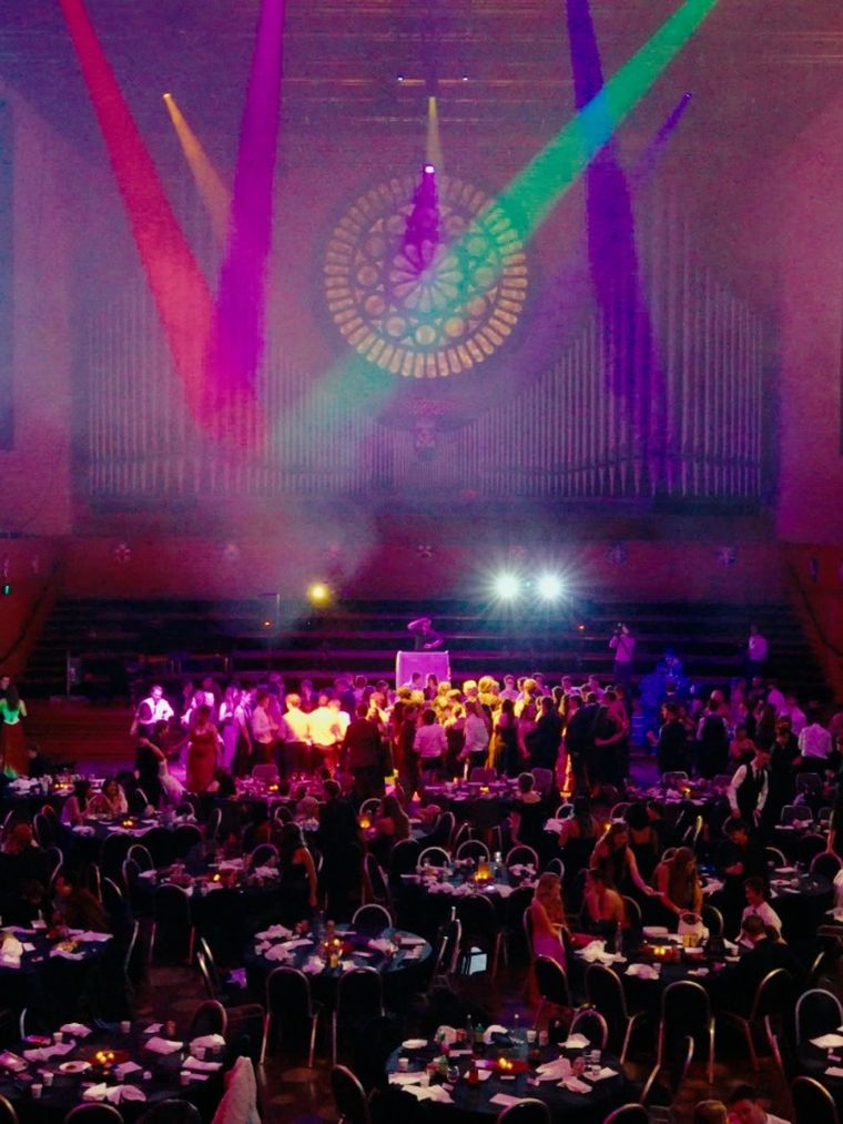 Ballroom under purple stage lighting at a university club ball